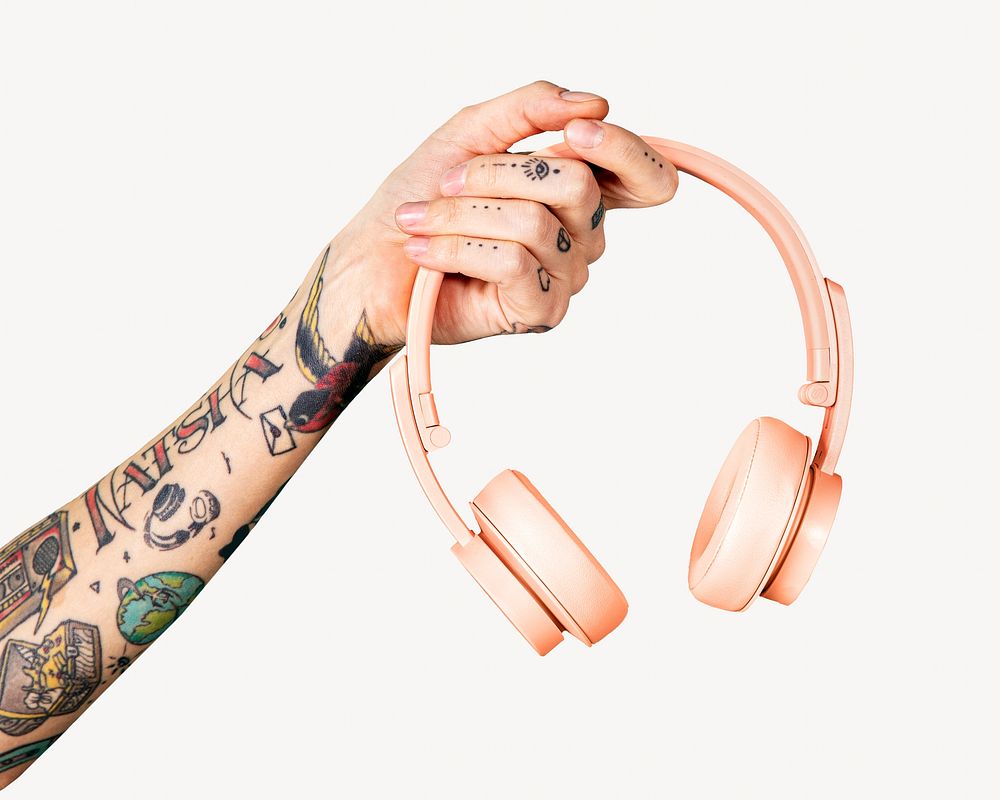 Tattooed arm holding pink headphones isolated image