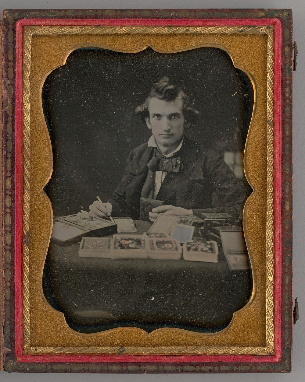 Untitled (Portrait of Seated Man Holding a Daguerreotype and Brush) by Samuel J. Miller