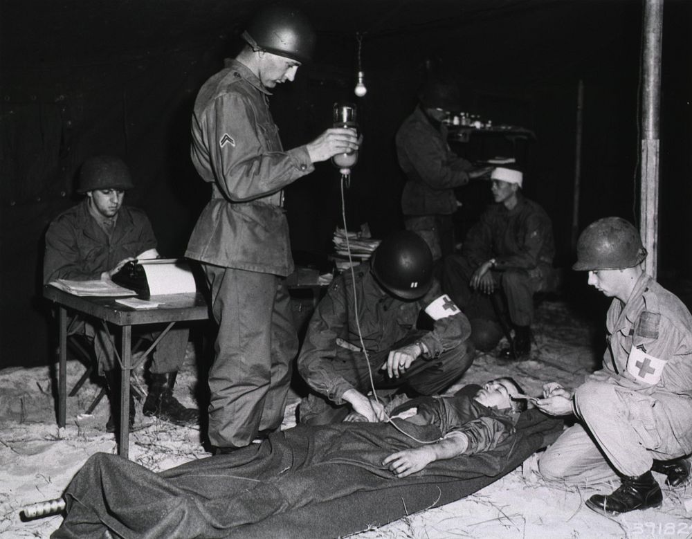 A casualty being treated by a doctor and two aidmen in the division surgery tent, 7 Dec. 1951 U.S. Signal Corps. The wounded…