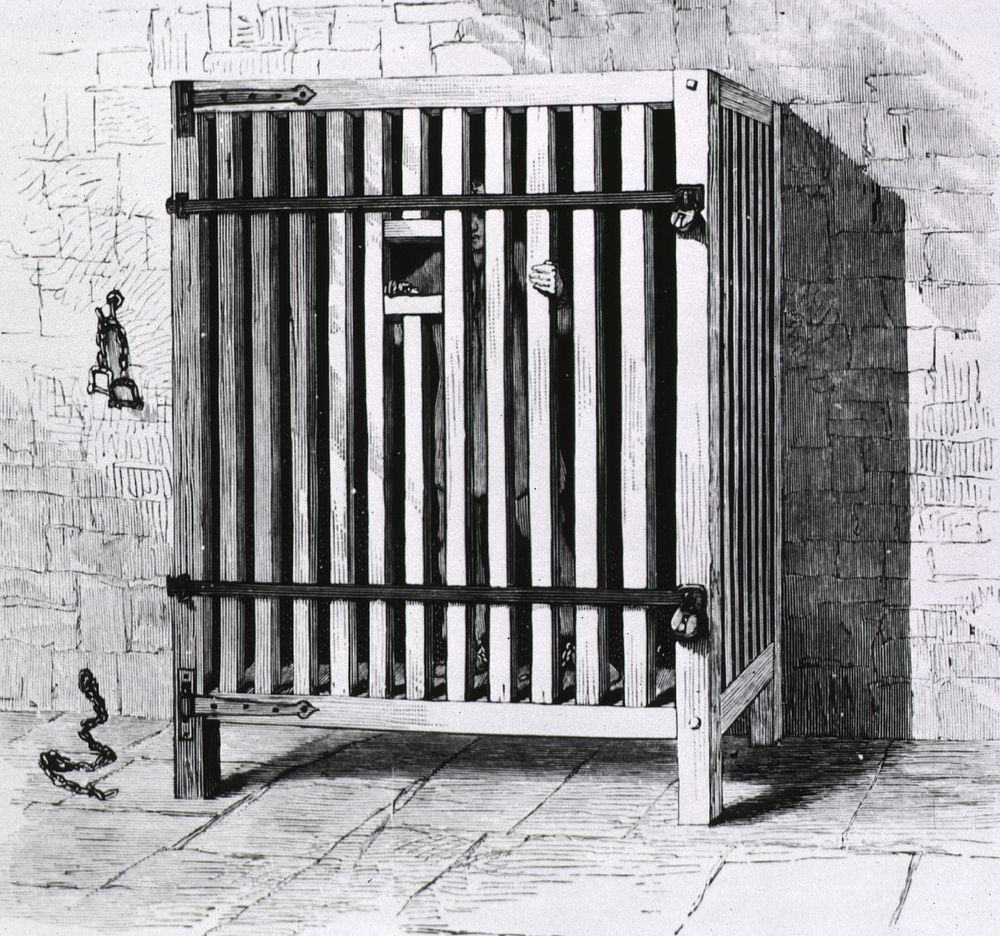 Belgian cage. A sturdy wooden cage with a small opening for meals to be passed through. Original public domain image from…