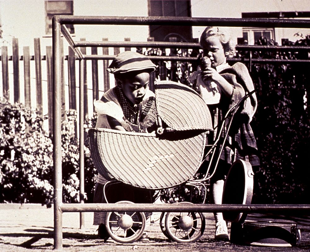 Two girls and a baby carriage. Abstract: On a sunny day in Calif. an African American girl is leaning into a baby carriage…