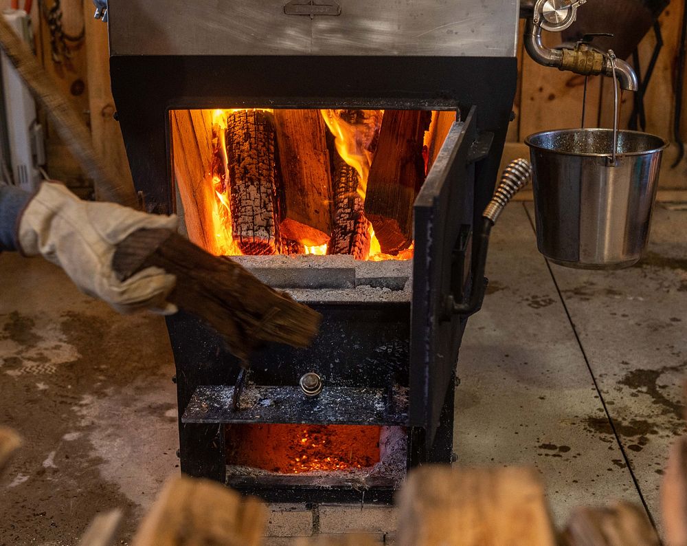 Joe Velovitch stokes the fire that is used to boil maple sap into syrup at Springboro Tree Farms in Brookston, Indiana.…