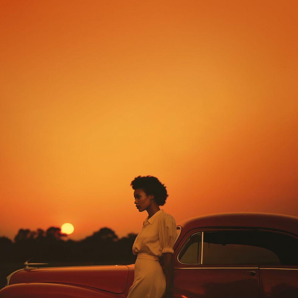 Woman standing by her car, sunset. 