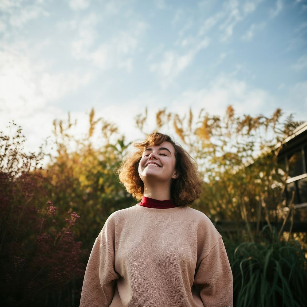 Girls wearing a sweatshirt laughing outdoors smile. 