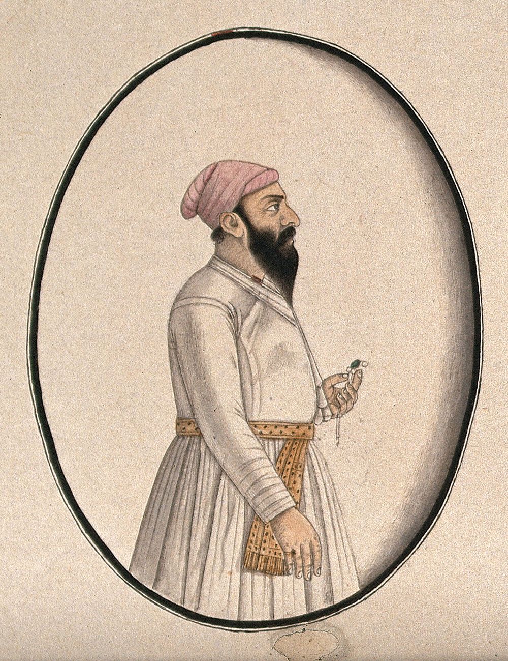 A Mughal courtier wearing a pink turban and holding an ornament . Watercolour drawing by an Indian artist.