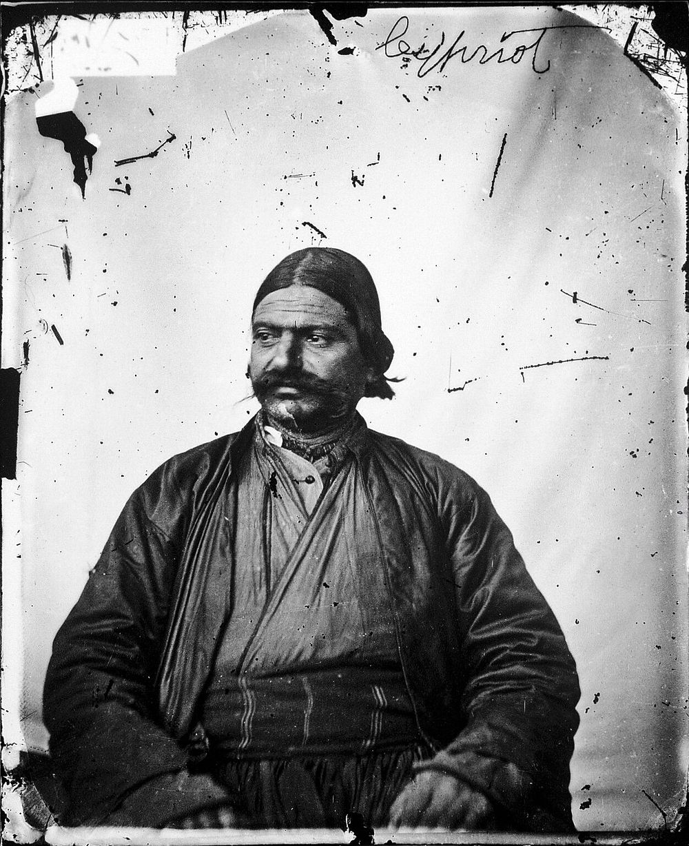 A seated Cypriot man, with a large moustache