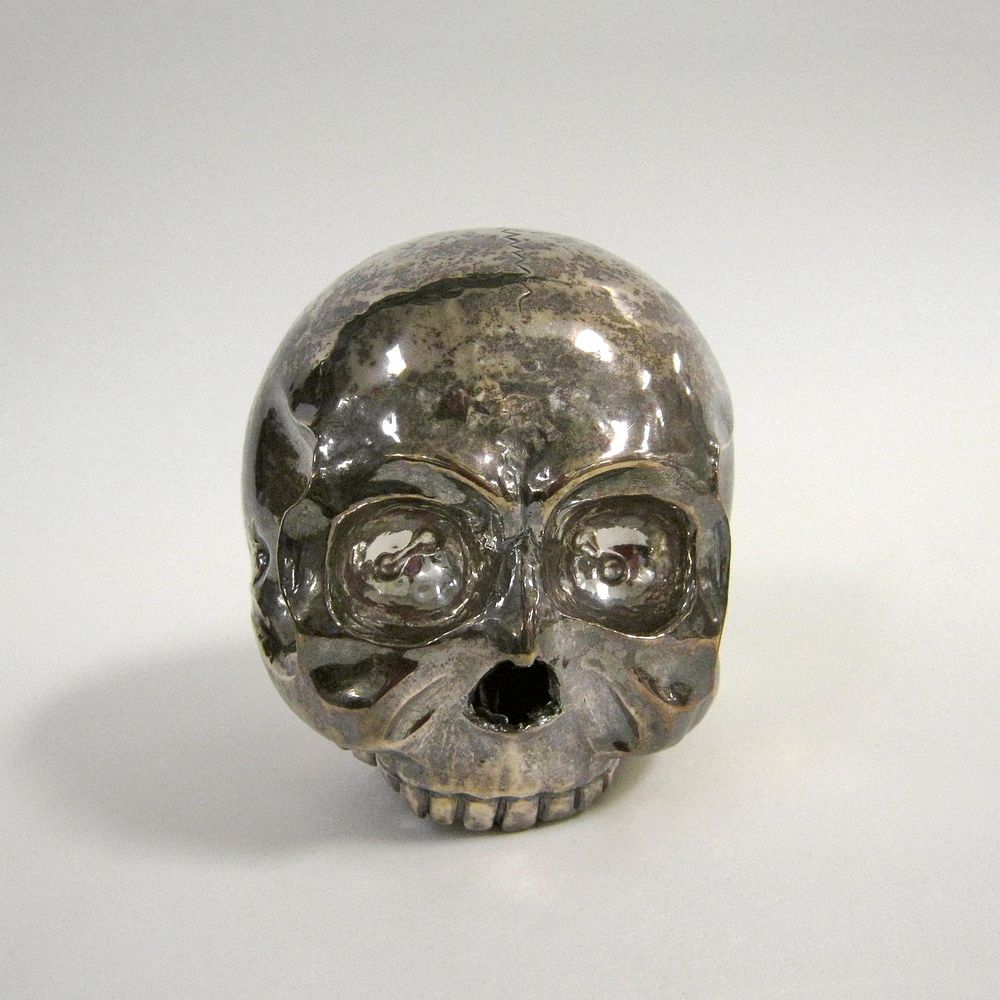 Skull, heavy, hammered and soldered silver work. A solder line bisects the skull vertically, parallel to the face. The…