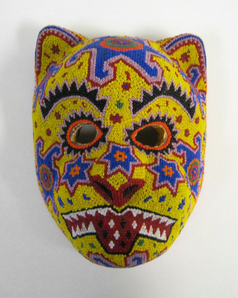 wood form of cat face covered overall in multicolored beads; yellow ground. Original from the Minneapolis Institute of Art.
