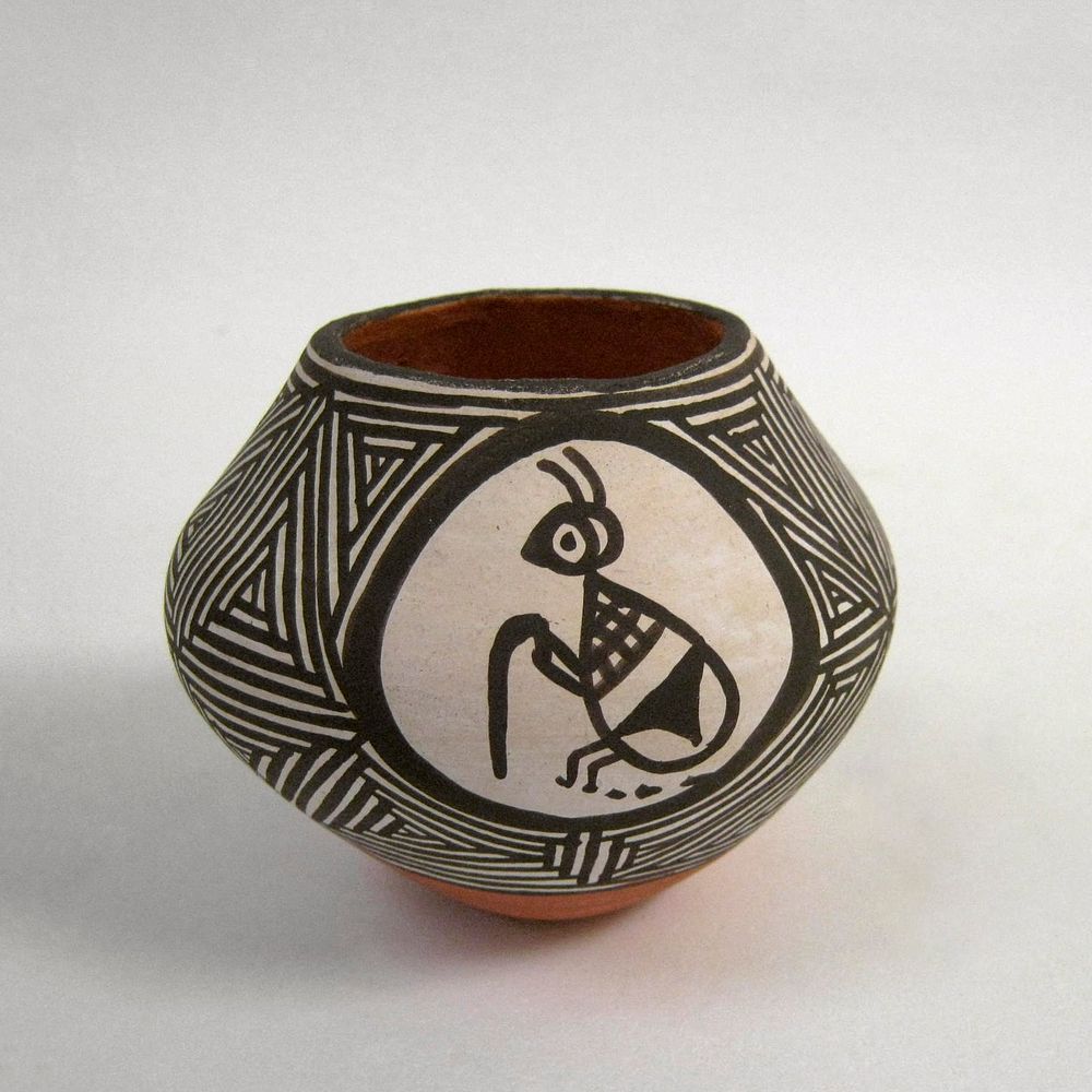 small vessel with small foot; wide shoulder; red body decorated with wide top geometric black and white band with 2…