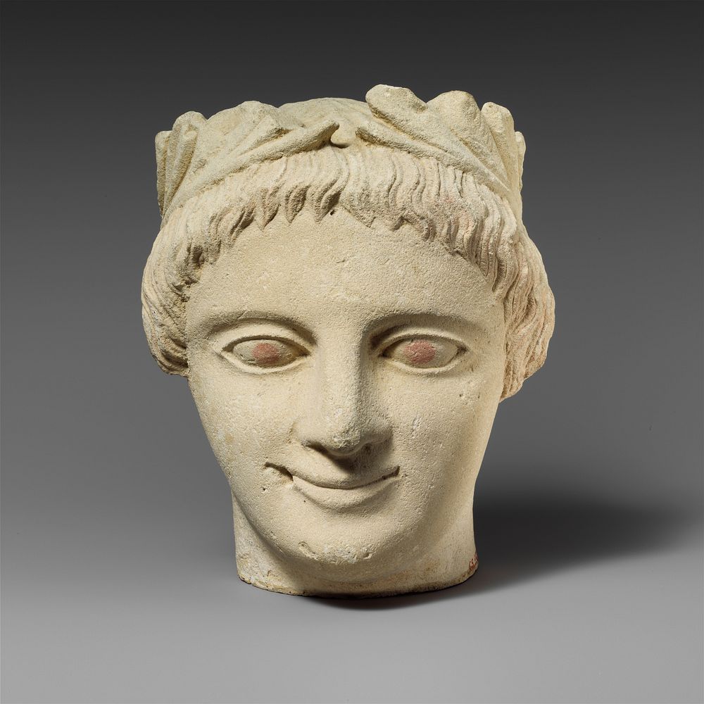Limestone head of a beardless male votary with a wreath of leaves