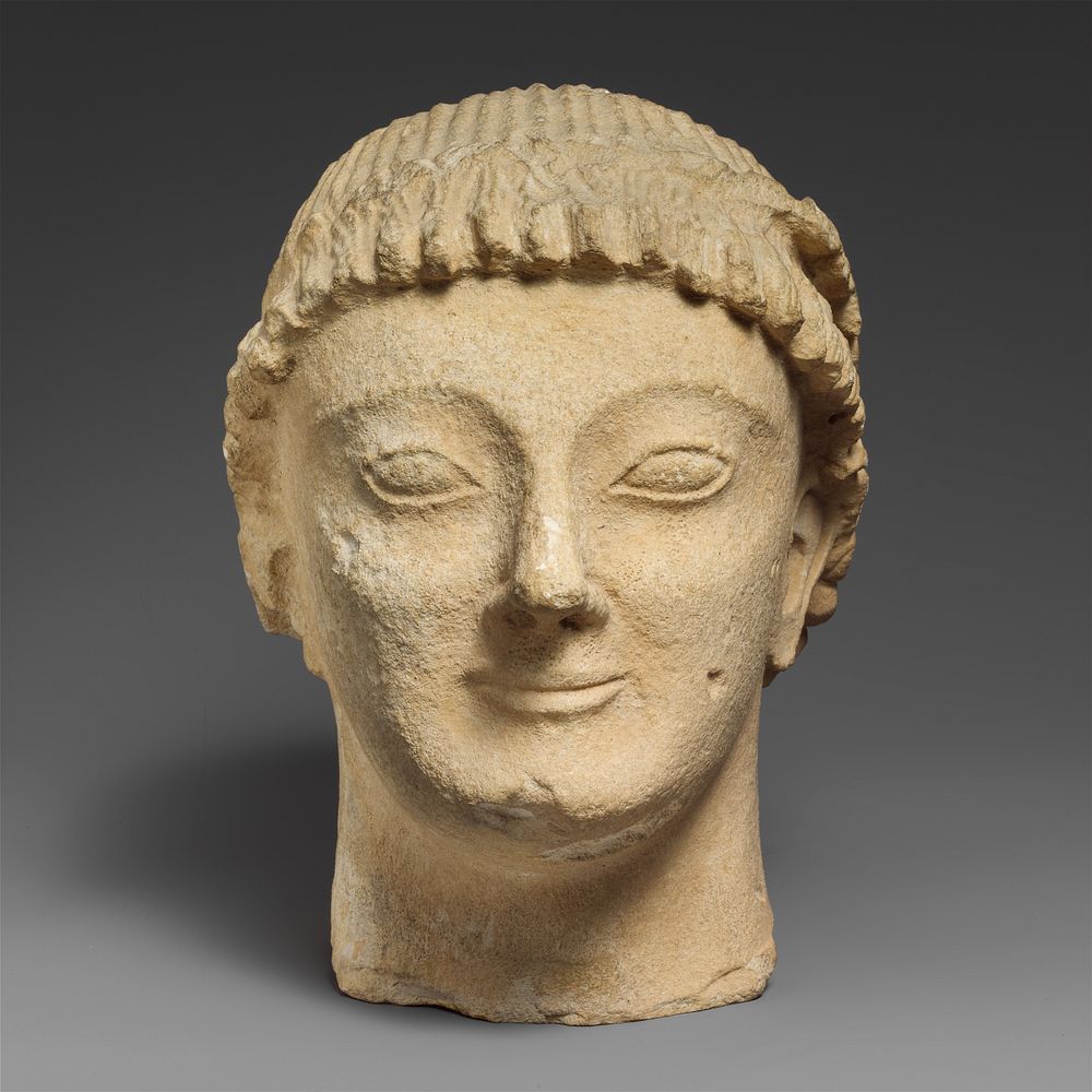 Limestone head of a beardless male votary with a wreath of rosettes