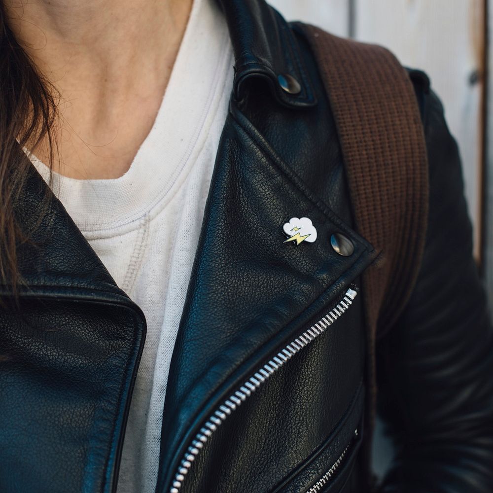Close up of cloud with lightning pin on leather jacket.