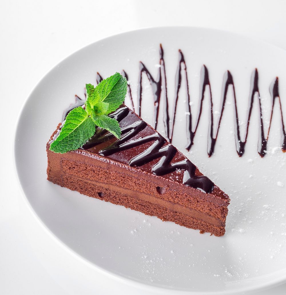 Free piece of chocolate cake with metled chocolate and mint leaves on top, public domain food CC0 photo.