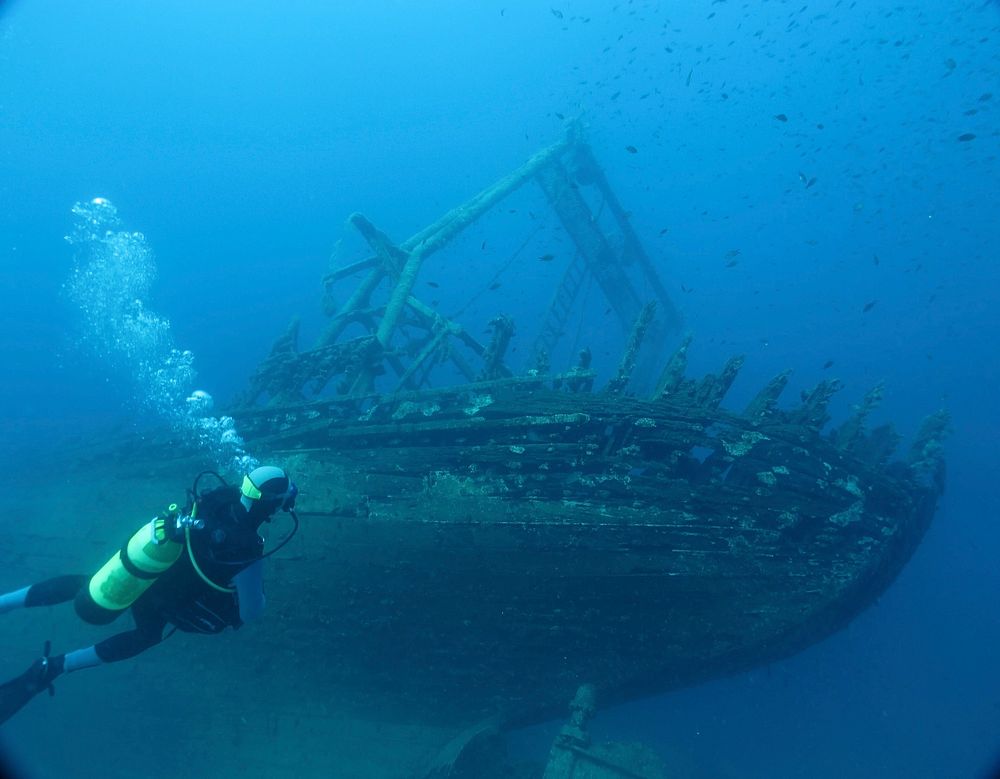 Free person scuba diving with abandoned wooden ship in background image, public domain underwater CC0 photo.