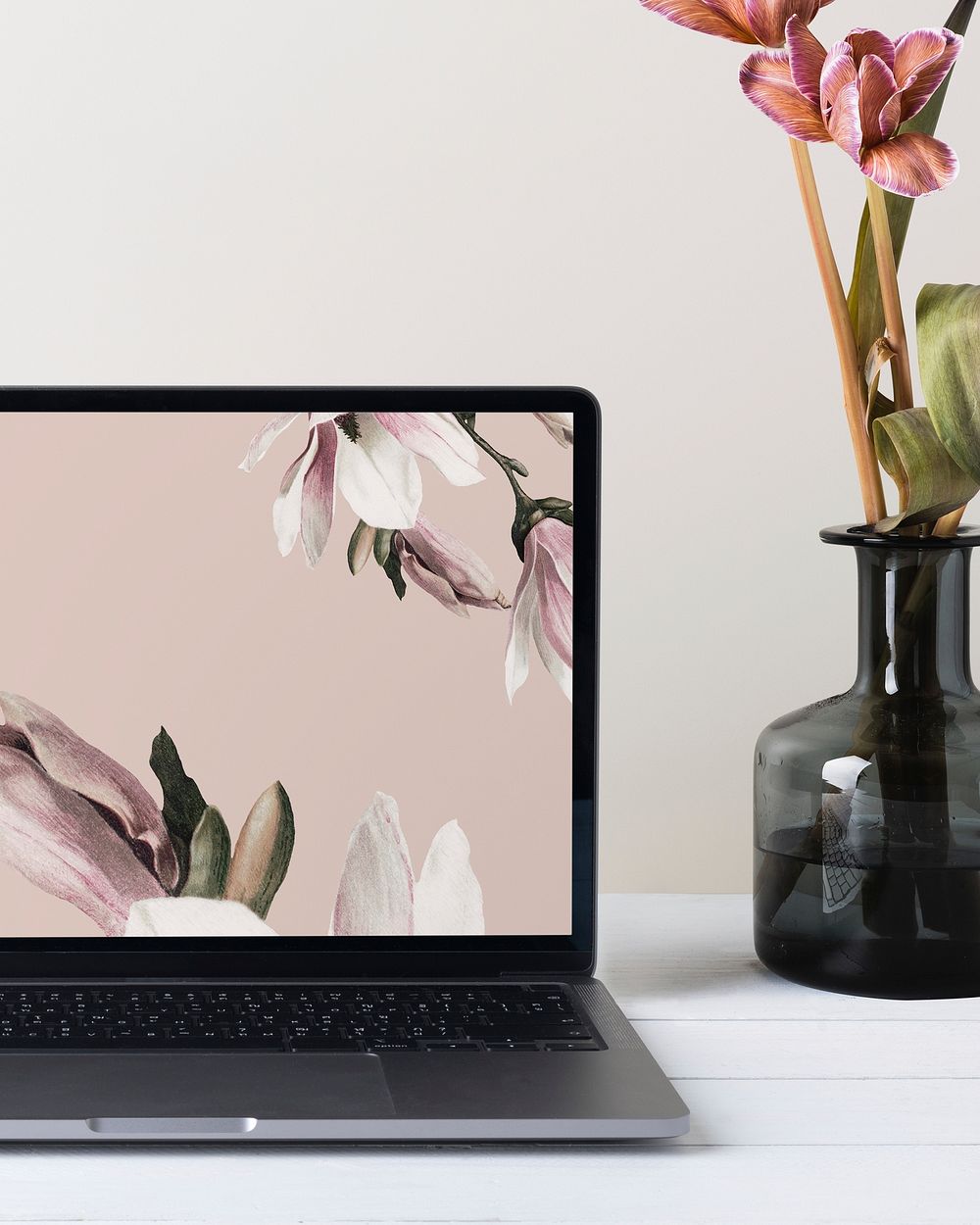 Laptop with aesthetic desktop wallpaper, flower in vase aside