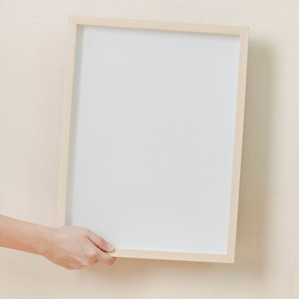Woman hanging blank frame on beige wall