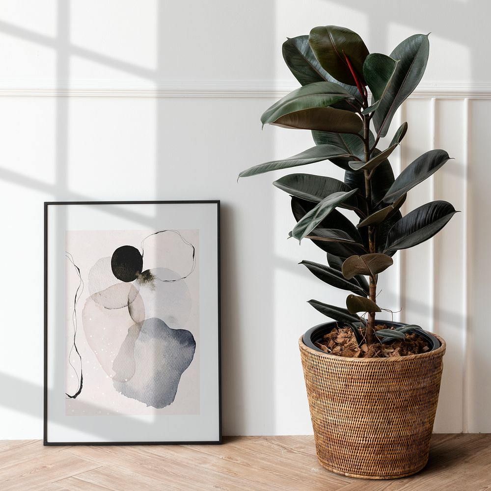 Picture frame mockup by a rubber plant on a wooden floor