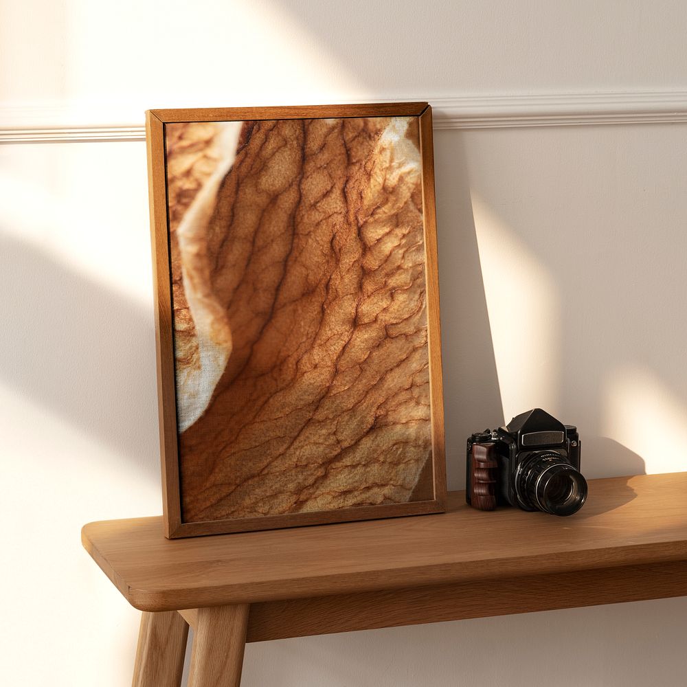 Picture frame mockup on a wooden sideboard table with an analog camera 