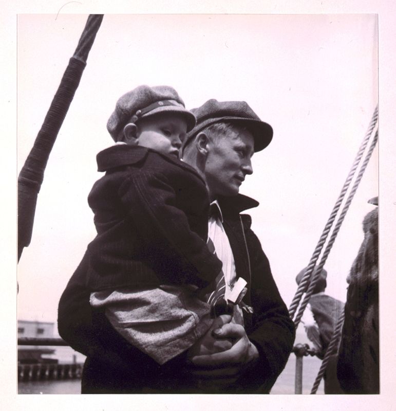 [Man with young boy in his arms, both wearing caps]. Sourced from the Library of Congress.