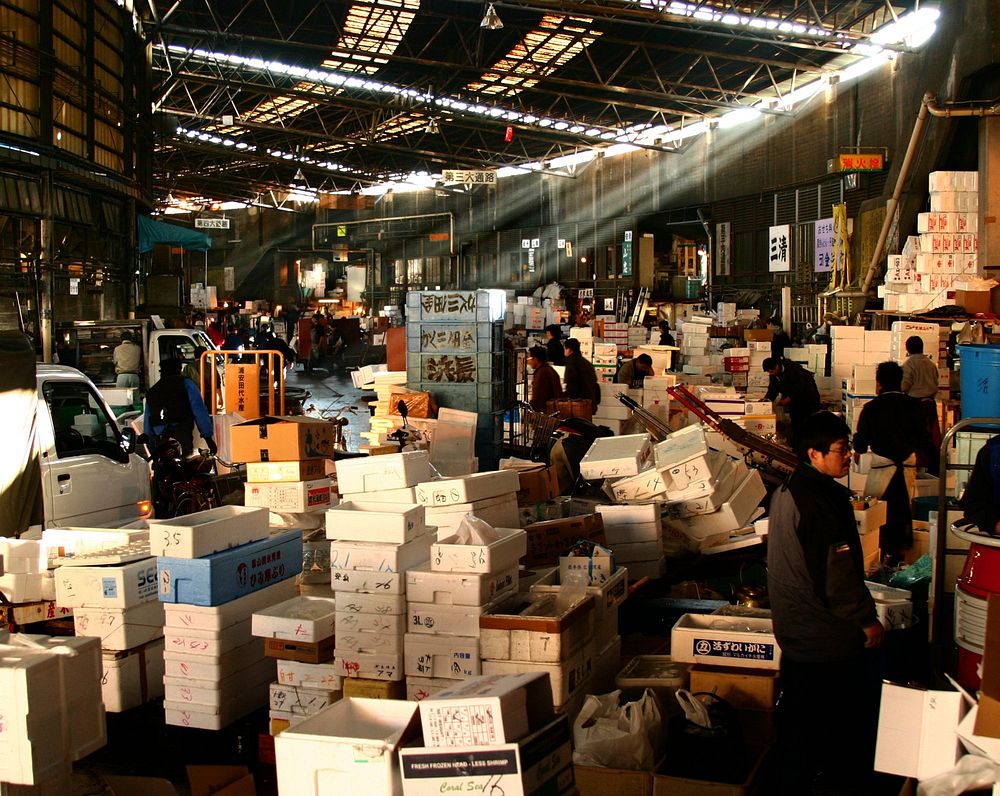 An indoor Japanese market is piles upon piles of styrofoam crates and boxes, the hustle and bustle of selling fresh goods.
