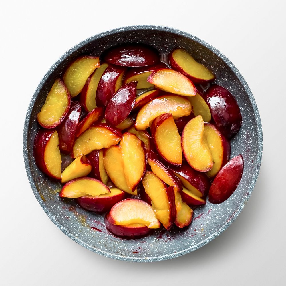 Sliced plums in bowl, fruit on white background, food photography
