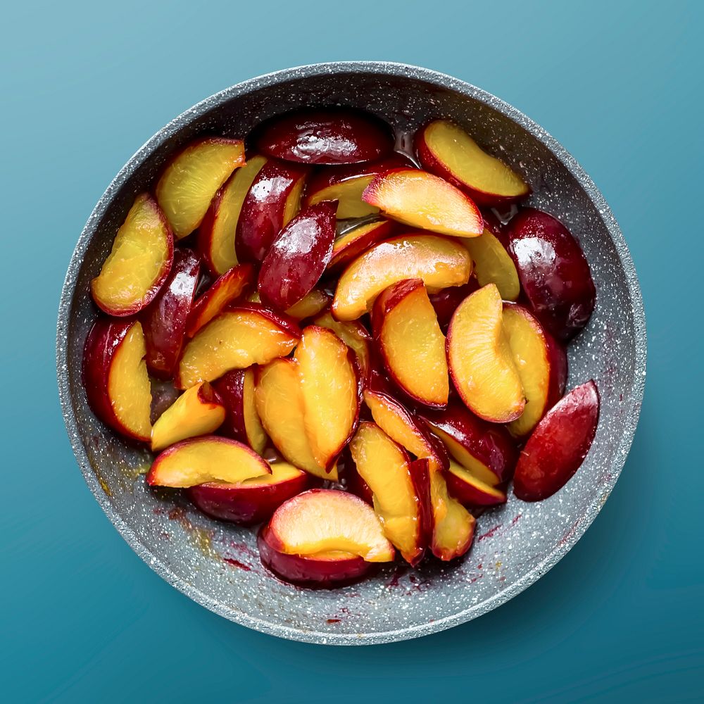 Sliced plums in bowl, fruit on blue background, food photography