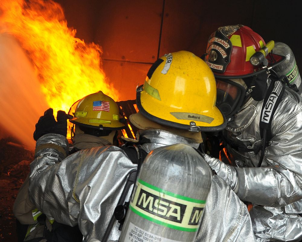 A U.S. Air Force firefighter instructs Honduran firefighters as they put out a mock structure fire during exercise Central…