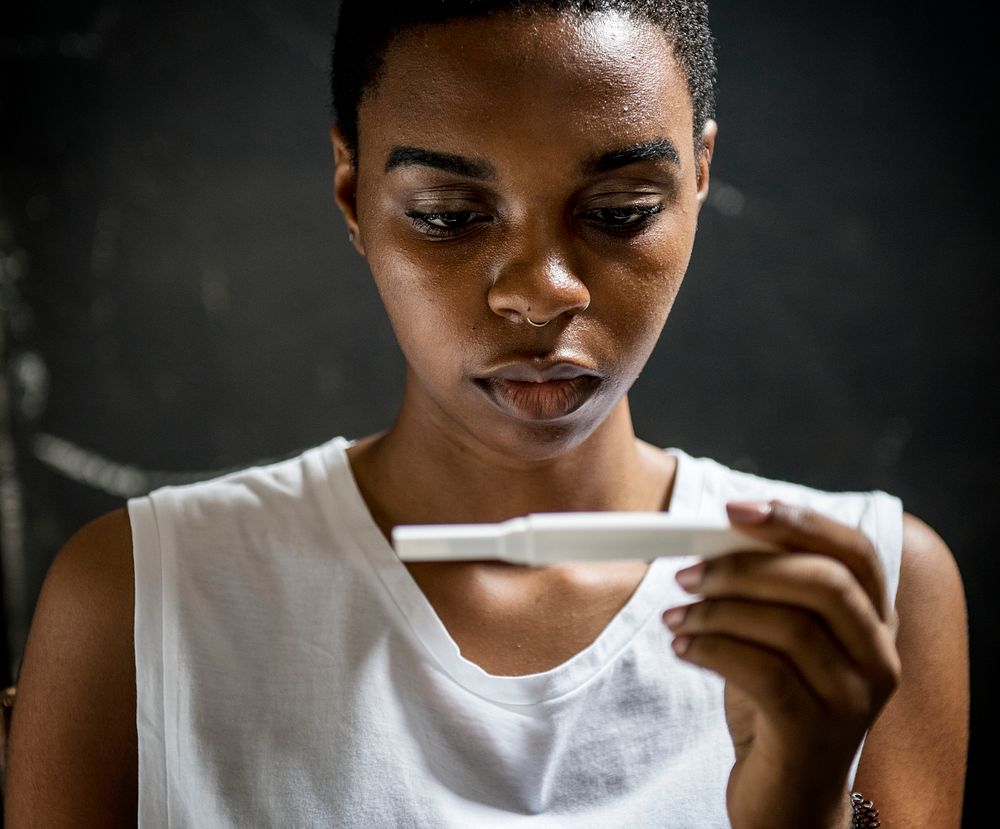 Closeup of black woman with pregnancy test in a hand