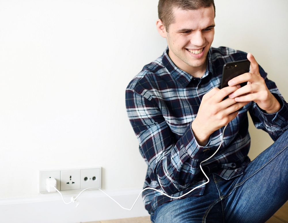 Smiling man using a smartphone at home