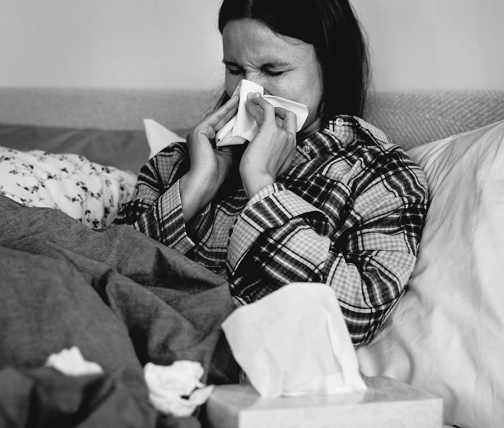 Sick woman sneezing in bed