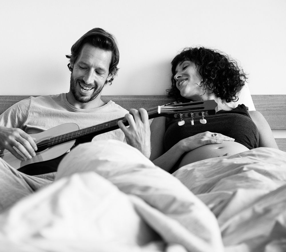 Man playing guitar for pregnant wife