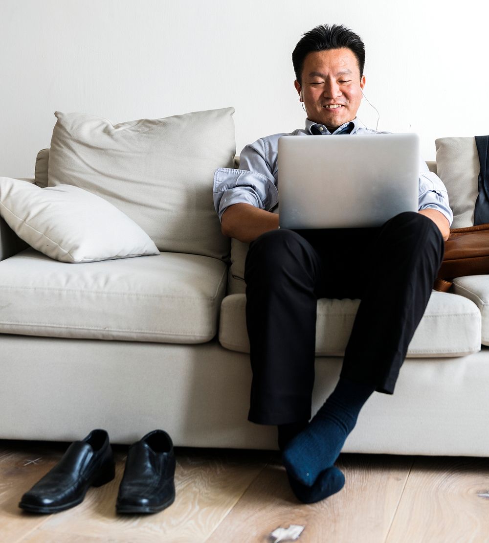 Asian businessman taking break laying on couch