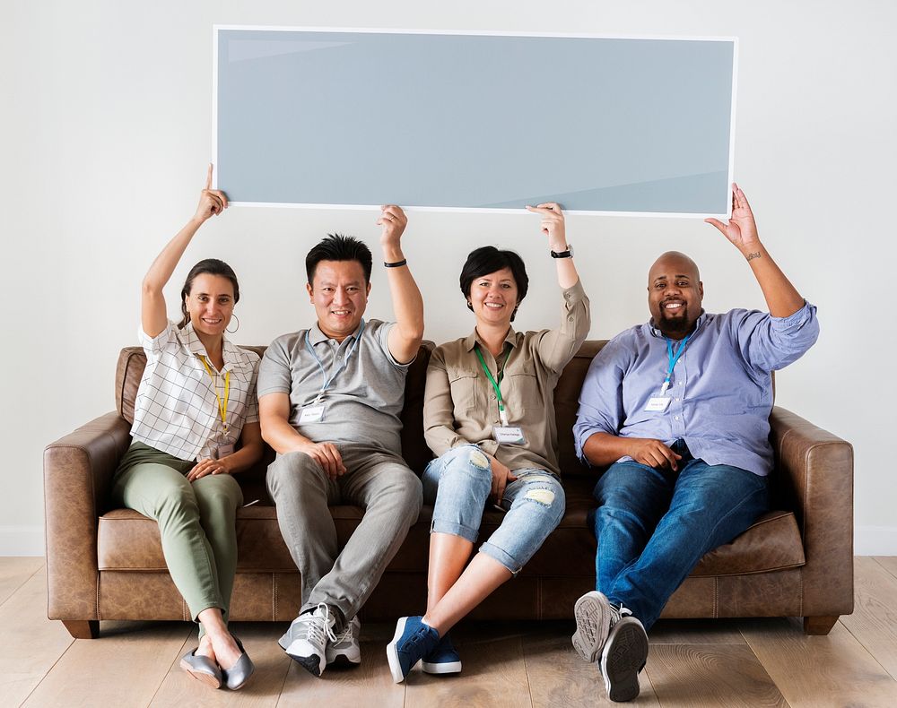 Diverse workers sitting on couch holding empty banner
