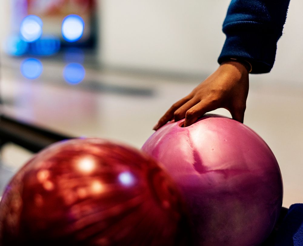 Girl picking up a bowling ball hobby and leisure concept