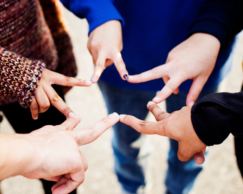 Group of friends using fingers to form the star shape teamwork and support concept