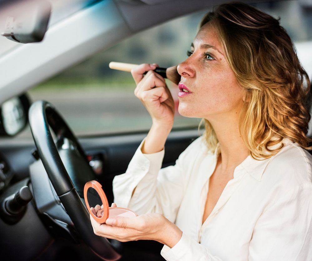 Woman wearing makeup in a car