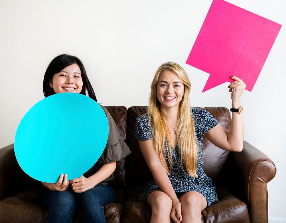 Happy Asian and Caucasian women friends holding copyspace speech bubble