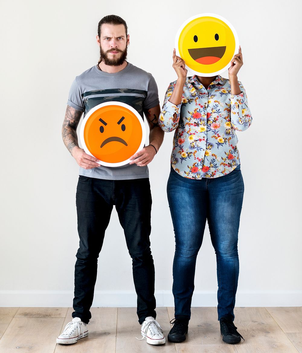Interracial couple holding an expressive emoticon face facial expression frown and smile relationship issue concept