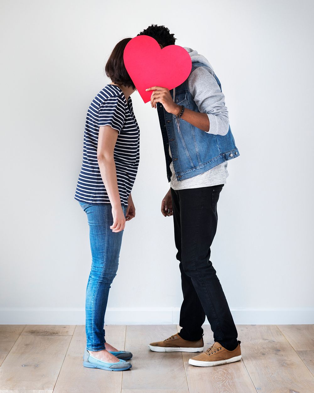 Interracial couple holding a red heart and kissing