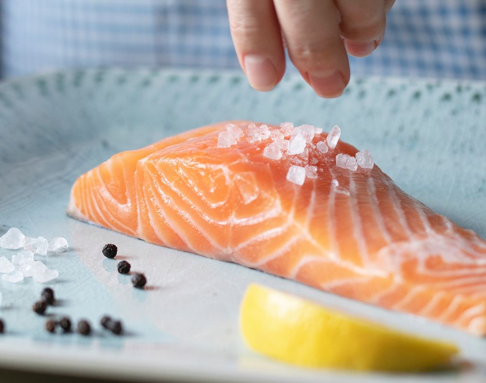 A person seasoning a fillet of salmon food photography recipe idea