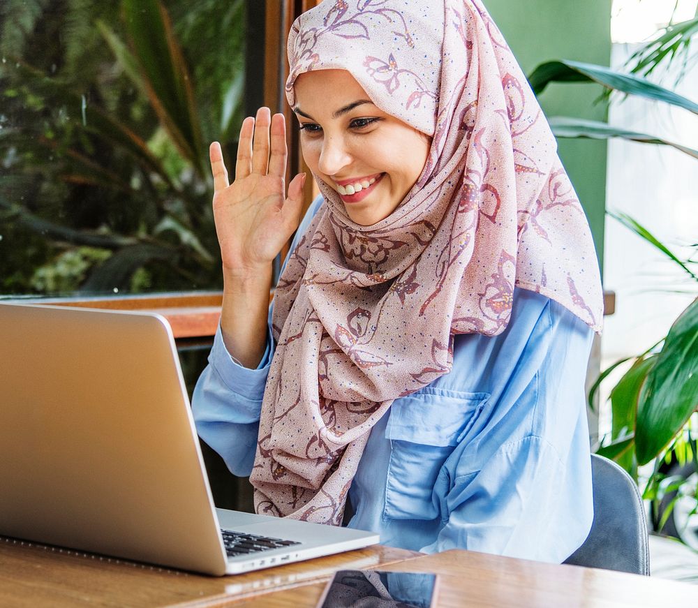 Islamic woman using laptop for video call with happy face