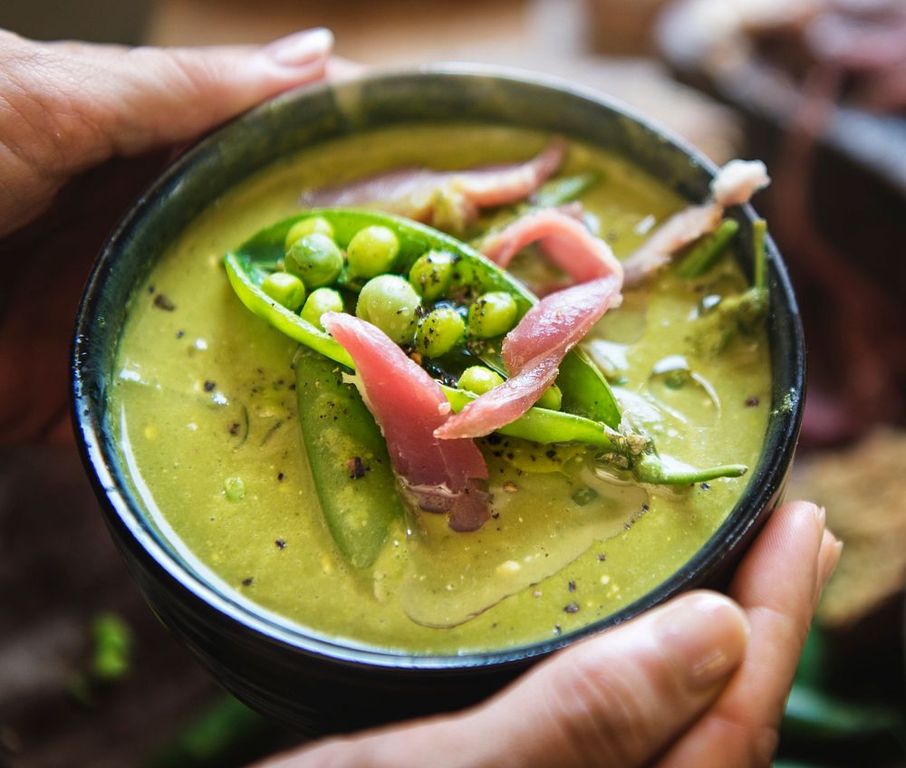 Close up of female hands holding green pea soup