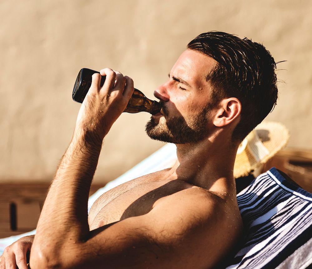 Man drinking a beer by the pool