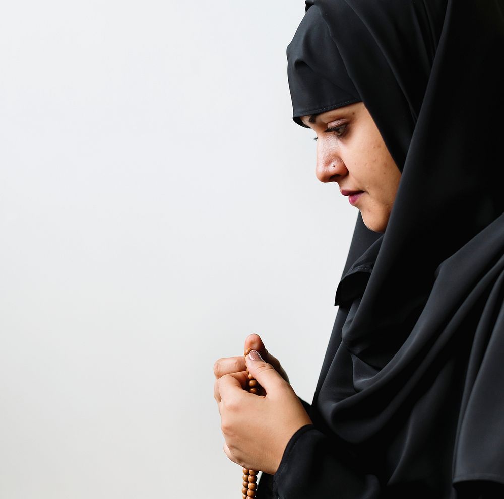 Muslim woman using misbaha to keep track of counting in tasbih