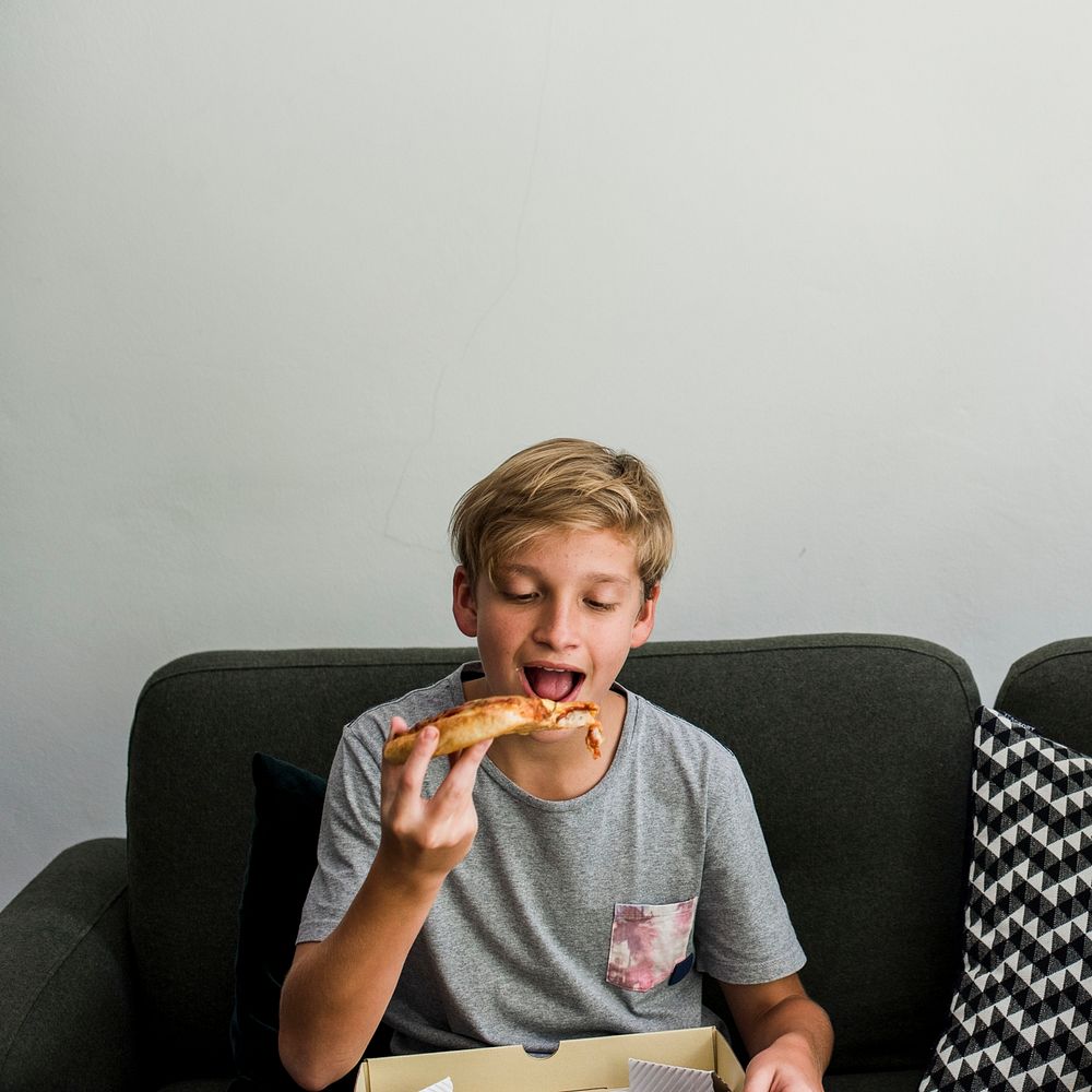 Young boy eating pizza on the couch