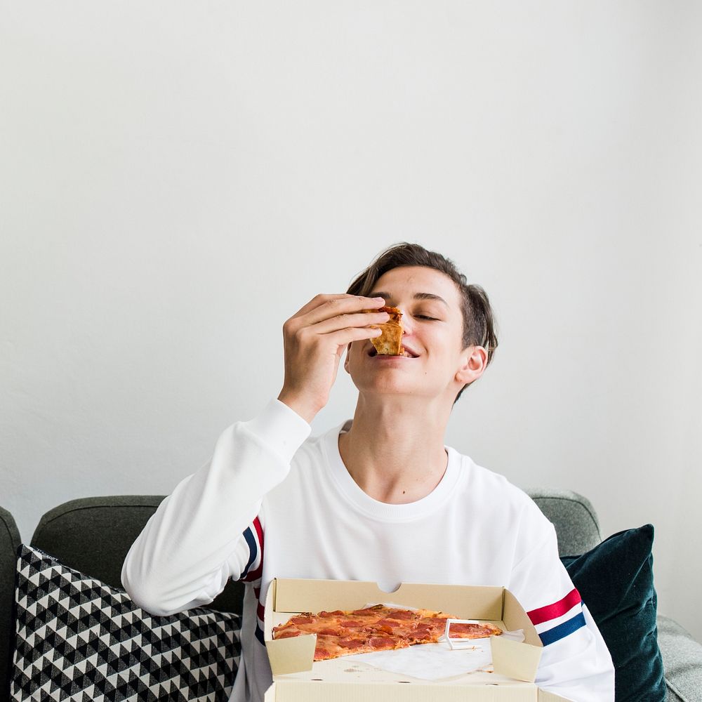Young boy eating pizza on the couch