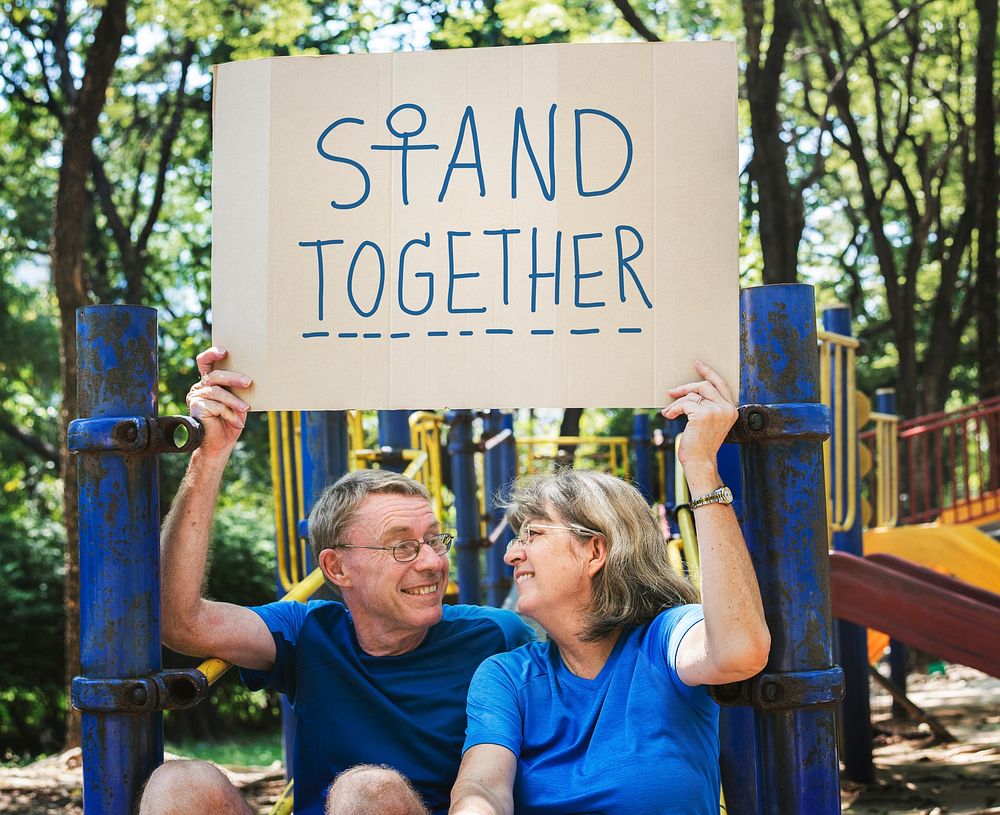 Mature couple holding a stand together signboard