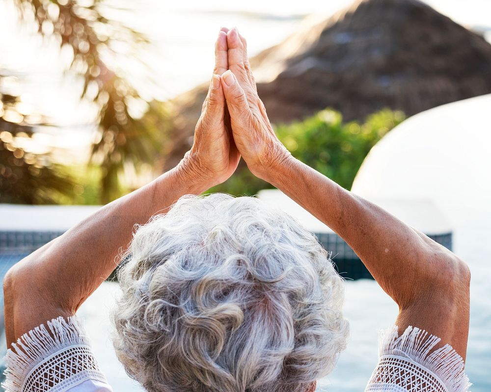 Senior adult practicing yoga by the pool