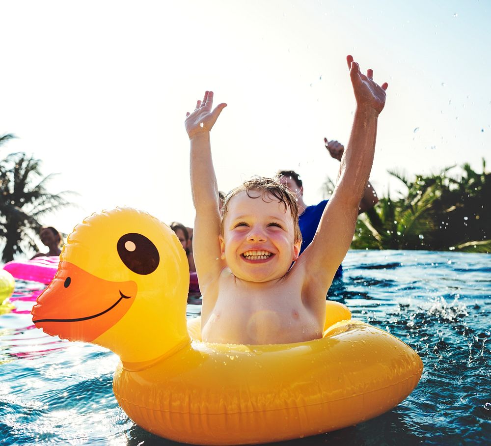 Happy boy and a yellow duck tube in the pool