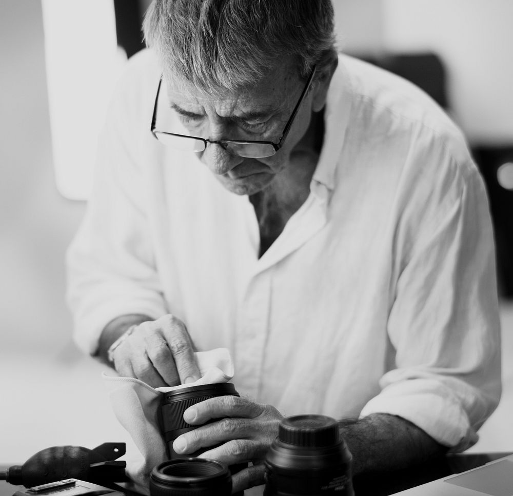 Senior photographer cleaning his lens